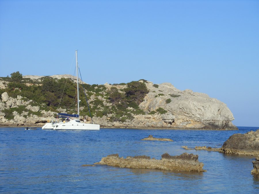 Segelkatamaran vor einer felsigen Küste bei Rhodos