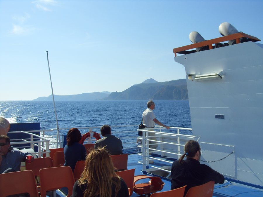 Fährdeck mit Reisenden und einer Inselküste im Hintergrund