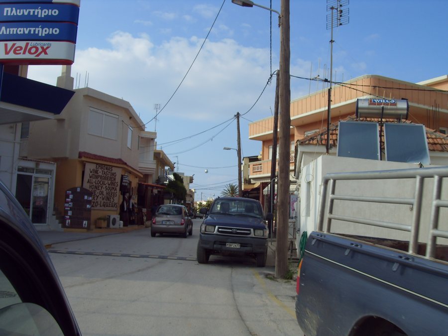 Straße mit Geschäften und parkenden Autos in einem Rhodos-Ort