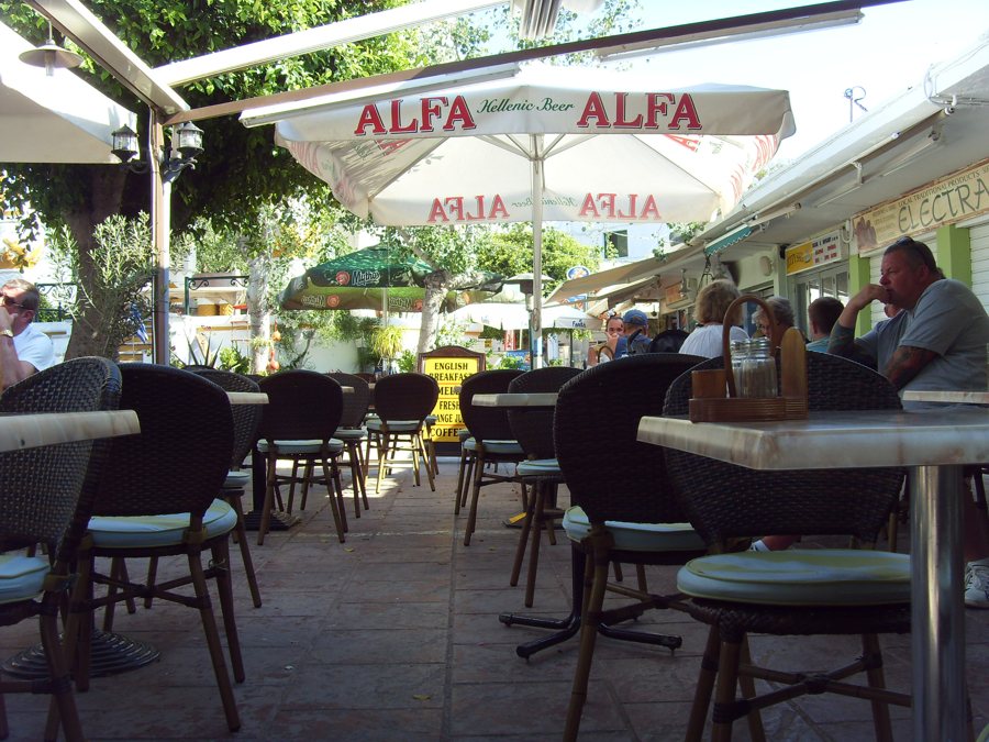 Caféterrasse mit Tischen und Gästen in Rhodos-Stadt.