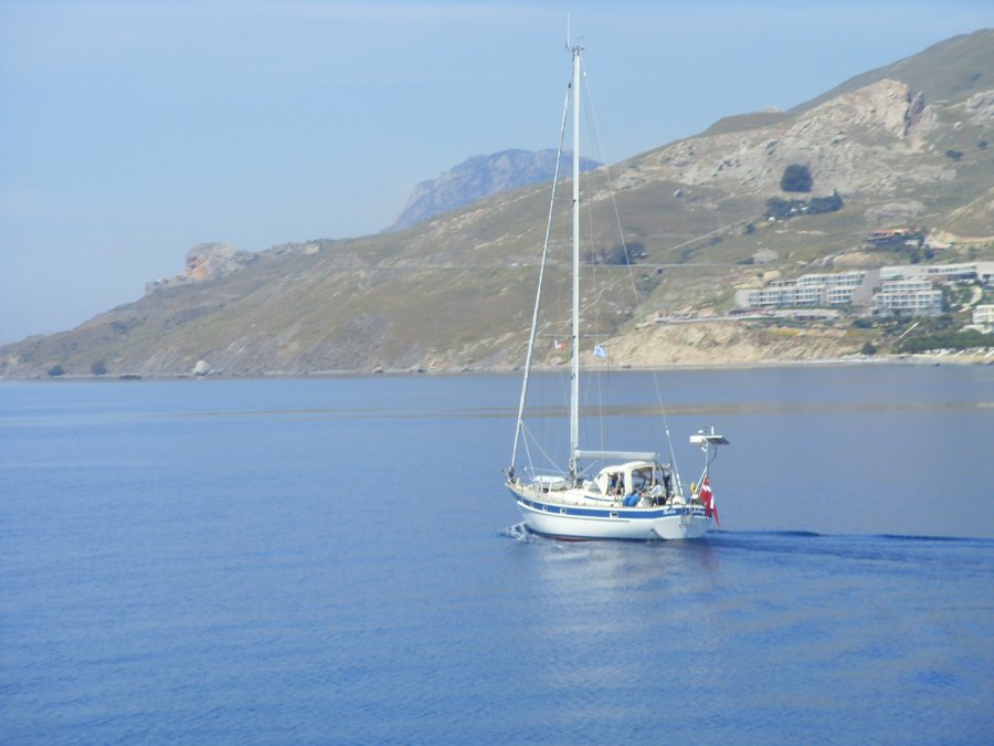 Segelboot vor einer trockenen Inselküste im Dodekanes