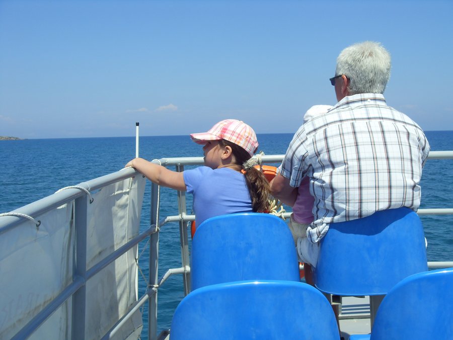 Erwachsene und Kind sitzen auf einer Fähre und blicken aufs Meer