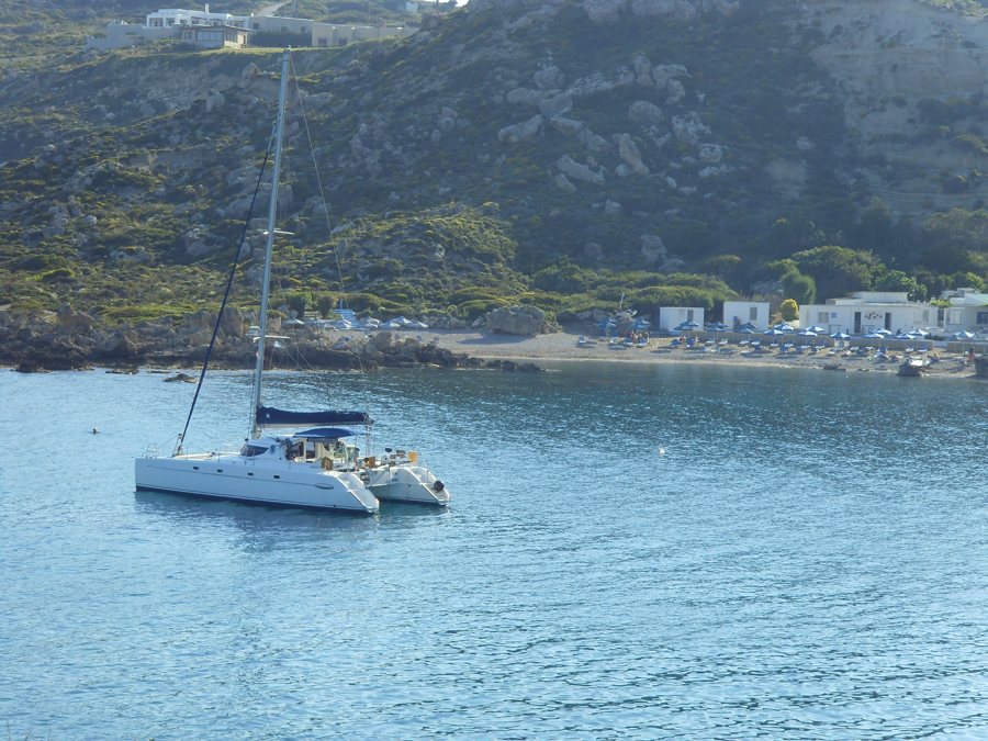 Katamaran vor einer bewachsenen Küstenbucht auf Rhodos